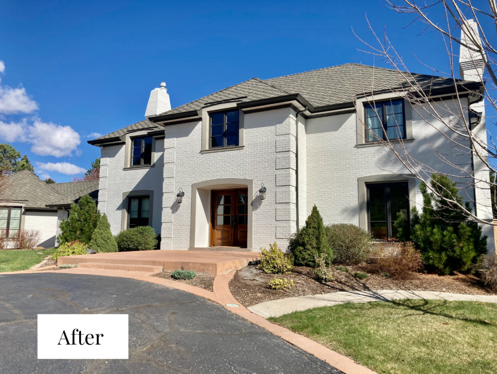 A white painted brick home features soft brown trim and light windows.