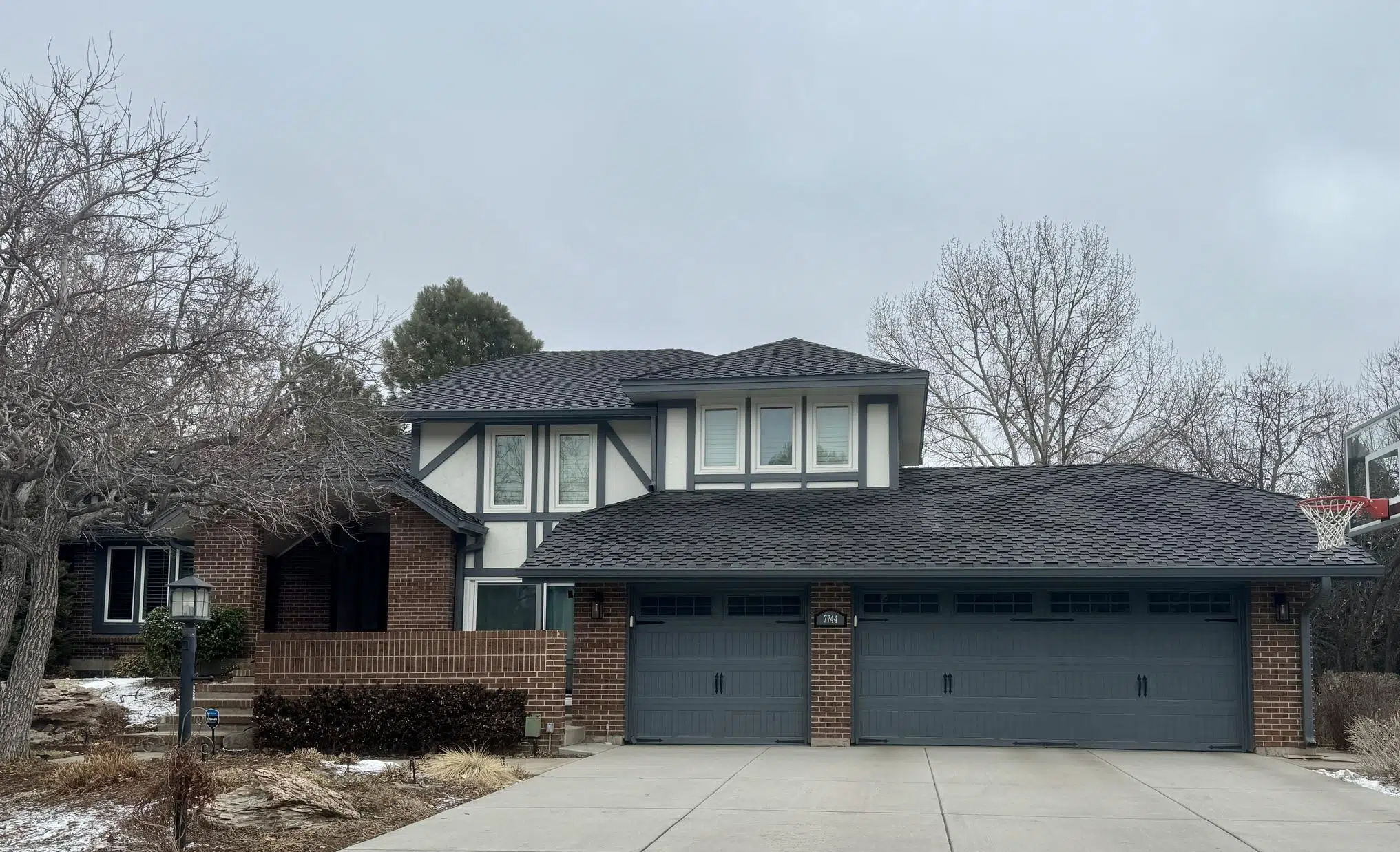 A modern Tudor home exterior features SW Web Gray exterior trim and SW Oyster White stucco.