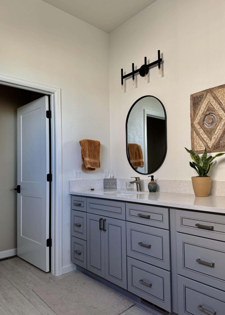 A home features Sherwin-Williams Alabaster bathroom walls with a gray vanity. 