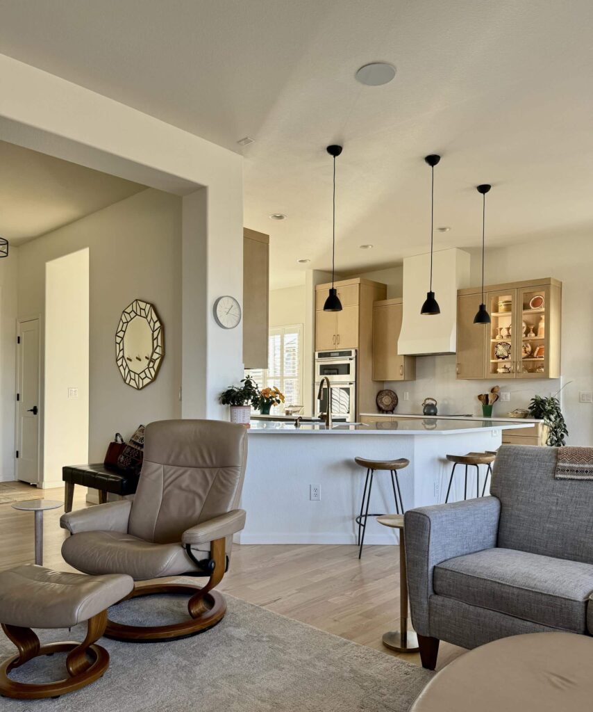 An open-concept kitchen and living room feature SW Alabaster walls with light wood cabinets. 