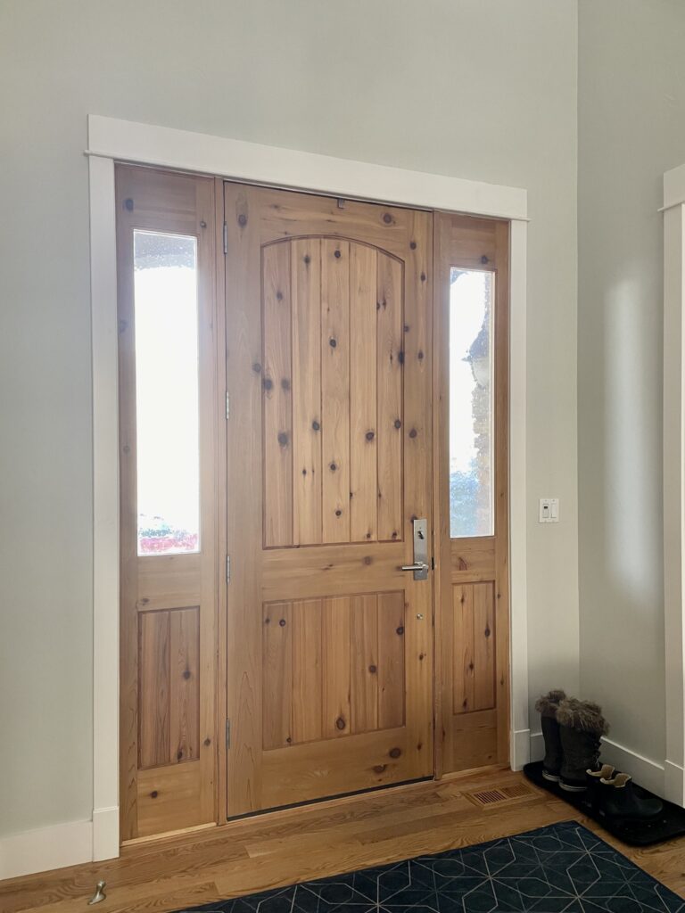 An entryway features BM Titanium paint and a natural wood front door. 