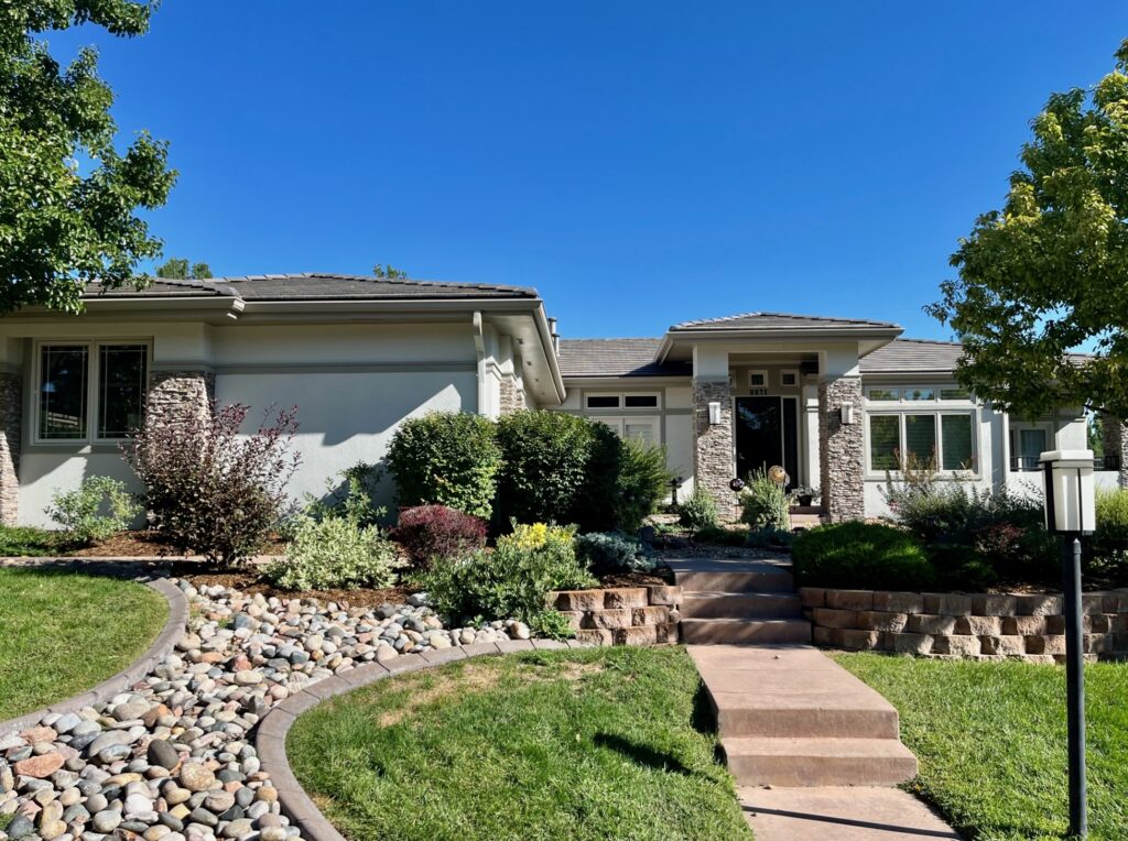 A home features SW Gossamer Veil exterior stucco siding and gray ledgestone.