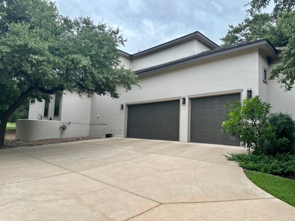 A home features SW Urbane Bronze garage doors with SW Accessible Beige stucco.