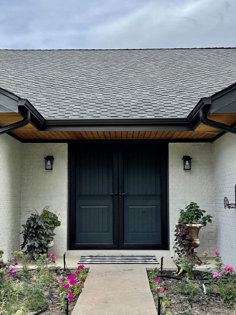 A home features SW Still Water painted front door with SW Gossamer Veil painted brick siding. 