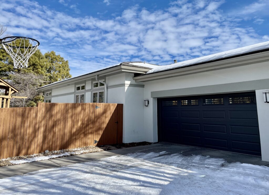 A home is painted with SW Gossamer Veil exterior paint and SW Iron Ore garage doors.