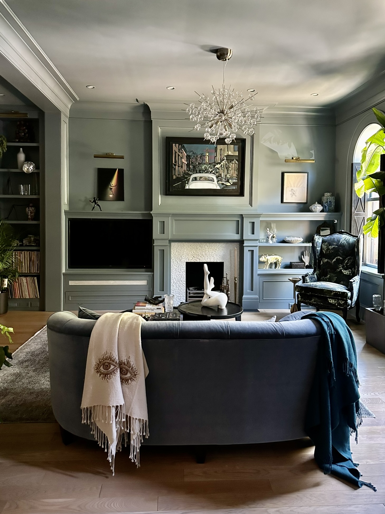 A living room features color drenching with Farrow & Ball de Nimes dark green paint.