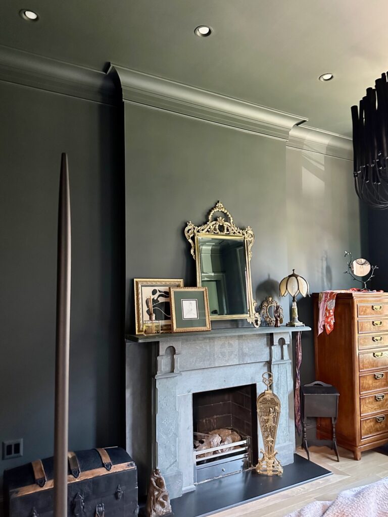 A color drenched bedroom is painted with Sherwin-Williams Rock Bottom dark green paint, including the color drenched fireplace