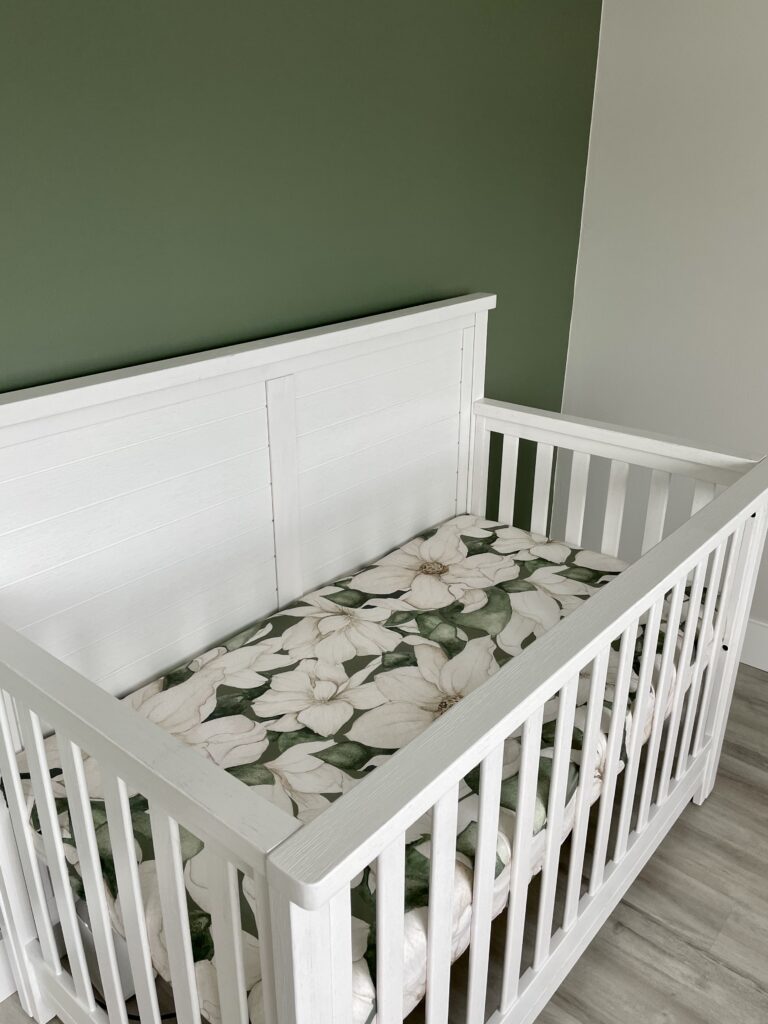 A nursery features a BM Rosepine green accent wall and BM Intense White walls.