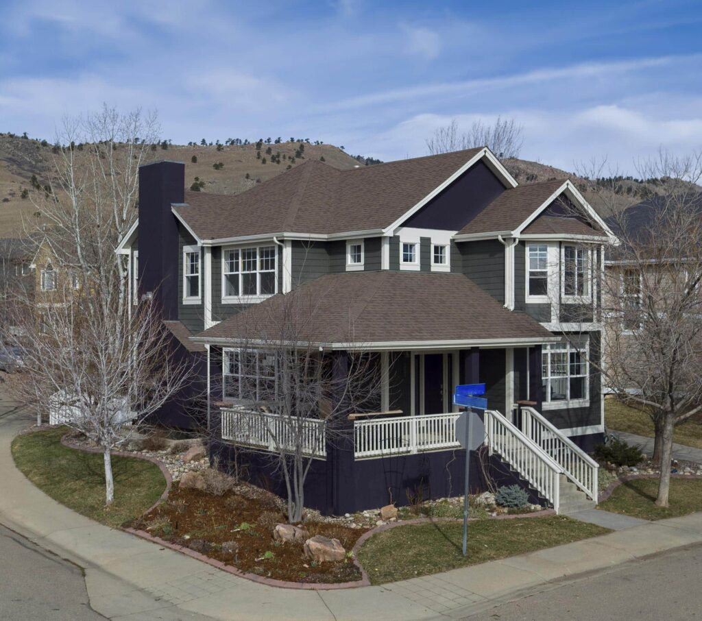 A house is painted with BM Ashwood Moss exterior paint and a Tulsa Twilight front door.