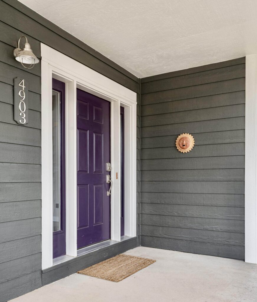 A house is painted with BM Ashwood Moss exterior paint and a Tulsa Twilight front door.