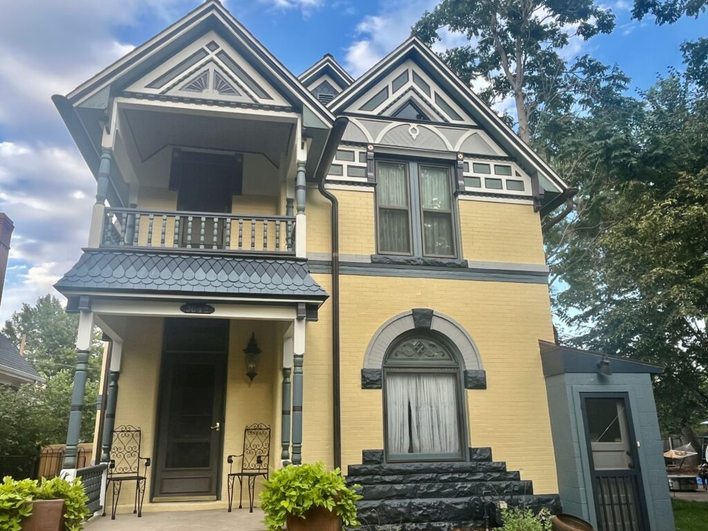 A Victorian home is painted with yellow exterior paint