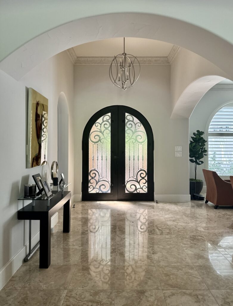 A Sherwin-Williams Egret White entryway features a black door and pinkish beige tile.