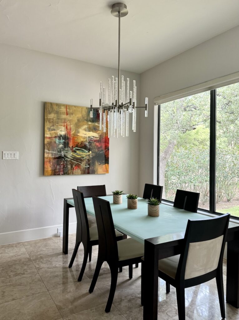 A Sherwin-Williams Egret White dining room with colorful wall art.