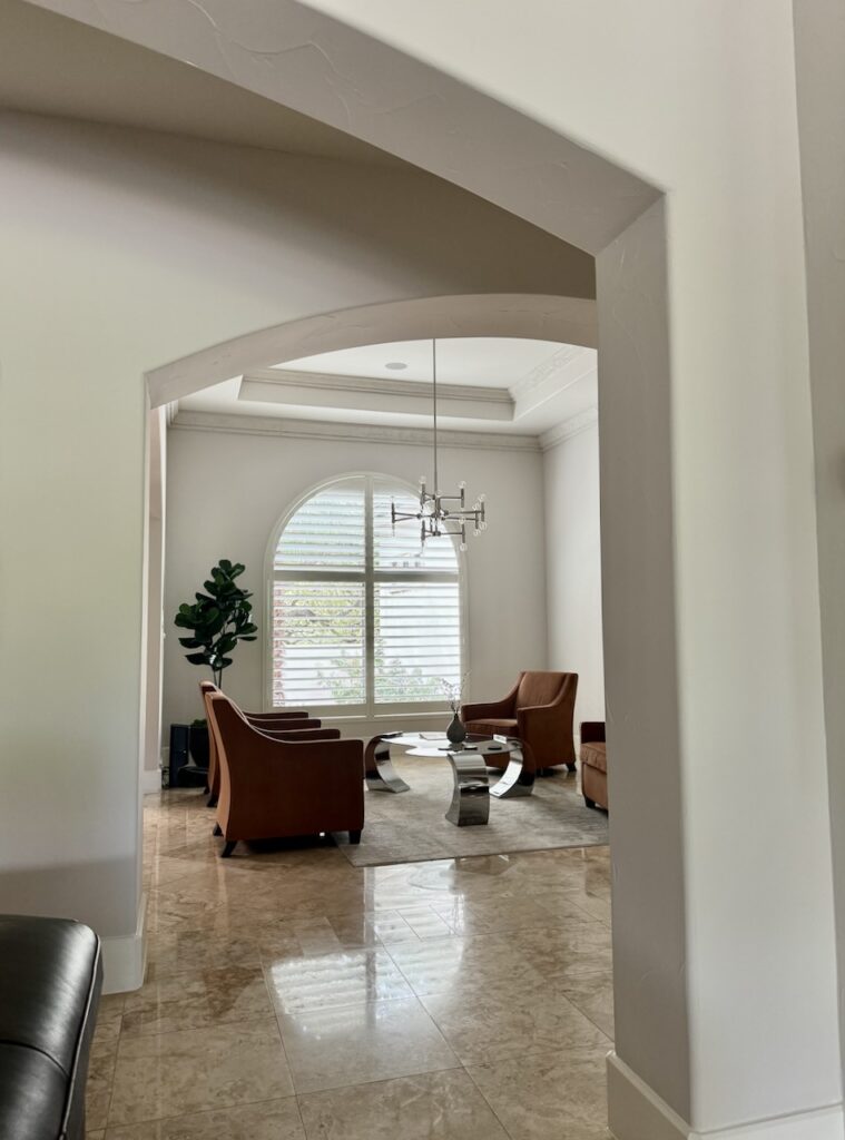 A Sherwin-Williams Egret White hallway with arches leading into a sitting room. Explore this color fully with The Color Concierge.