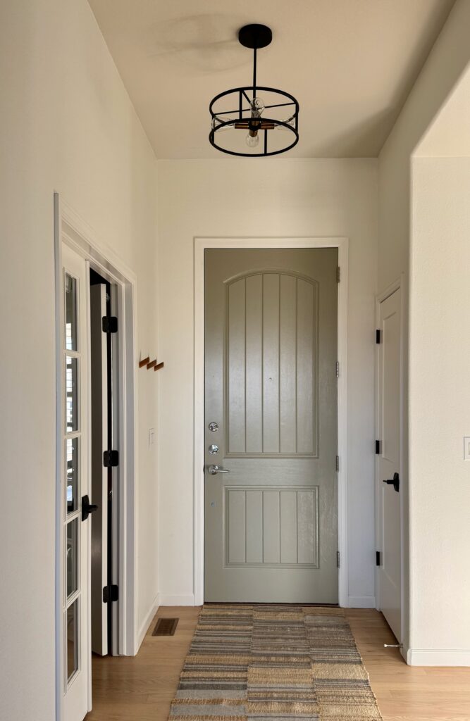 A painted interior front door is painted with a muted green hue, BM Springfield Sage.