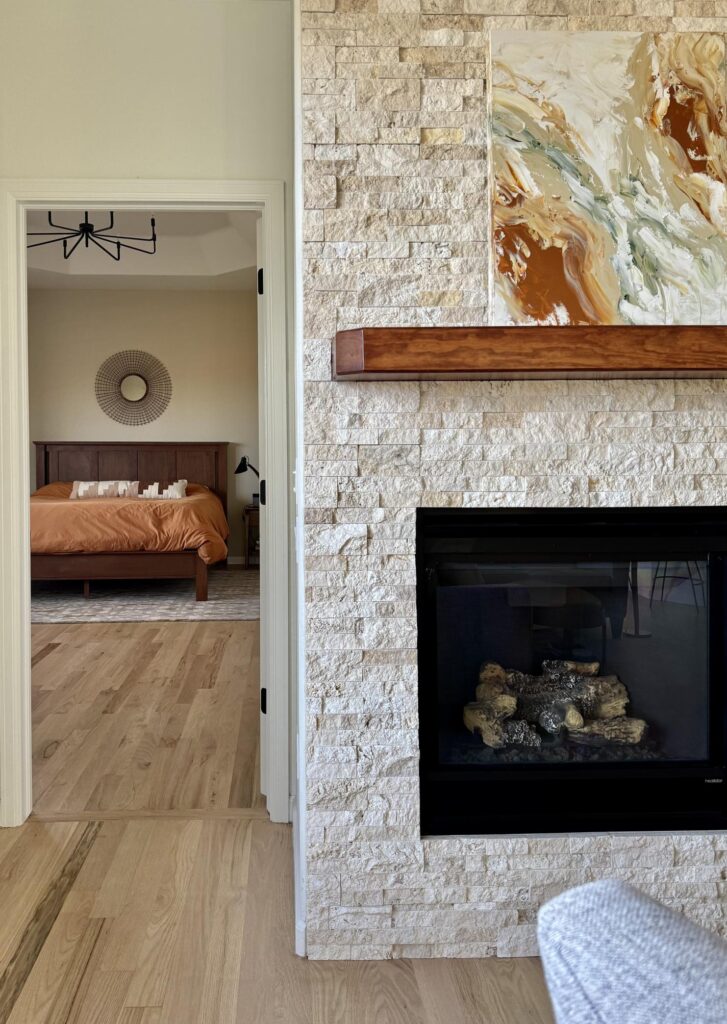 BM Natural Linen bedroom walls are seen through a doorway next to a Limestone fireplace.