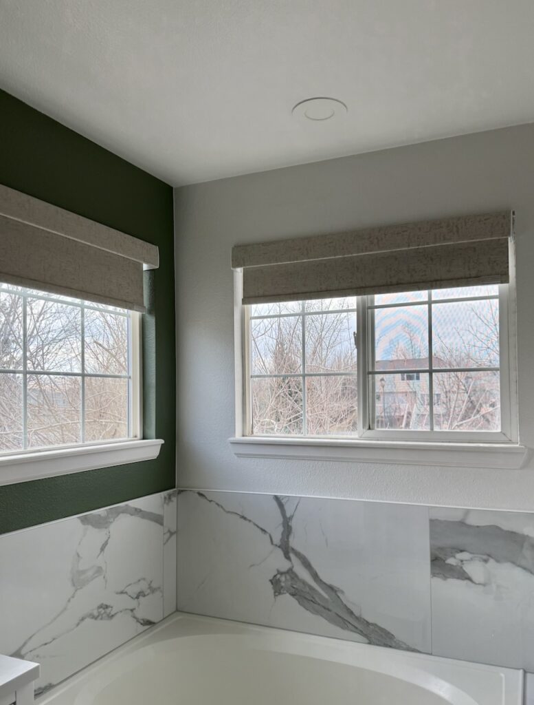 A bathroom features SW Snowbound walls and a dark green accent wall. 