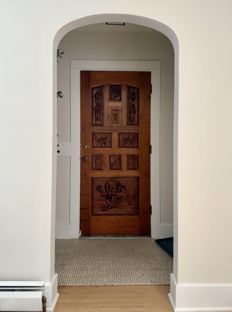 An entryway painted with SW Shoji White with a wooden front door.