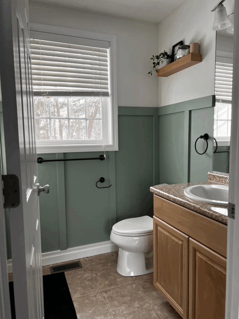 A bathroom features BM White Dove walls and BM Herb Bouquet board and batten paneling. 