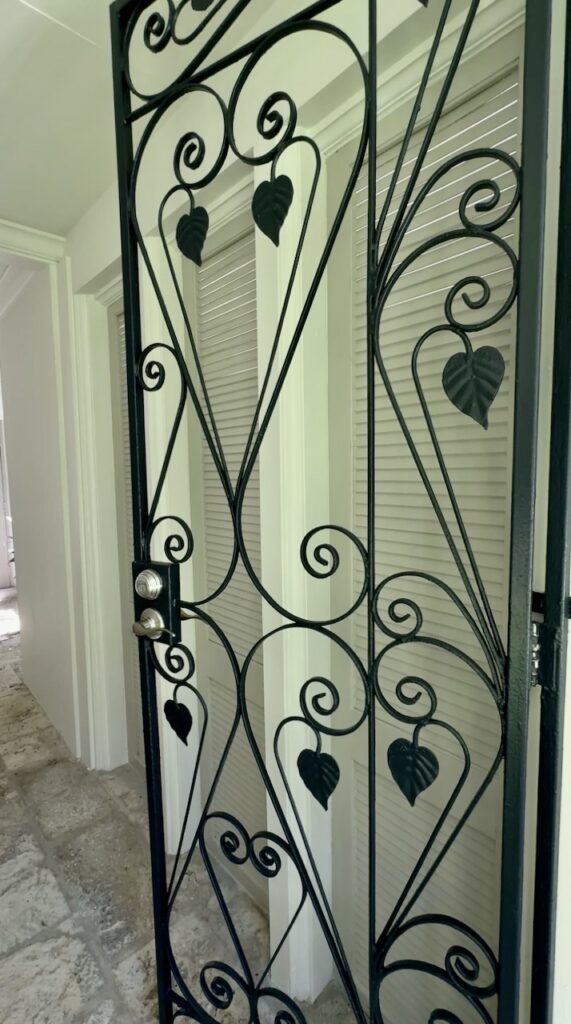 A home features Sherwin-Williams Inkwell iron front gate with SW MIndful Gray doors.