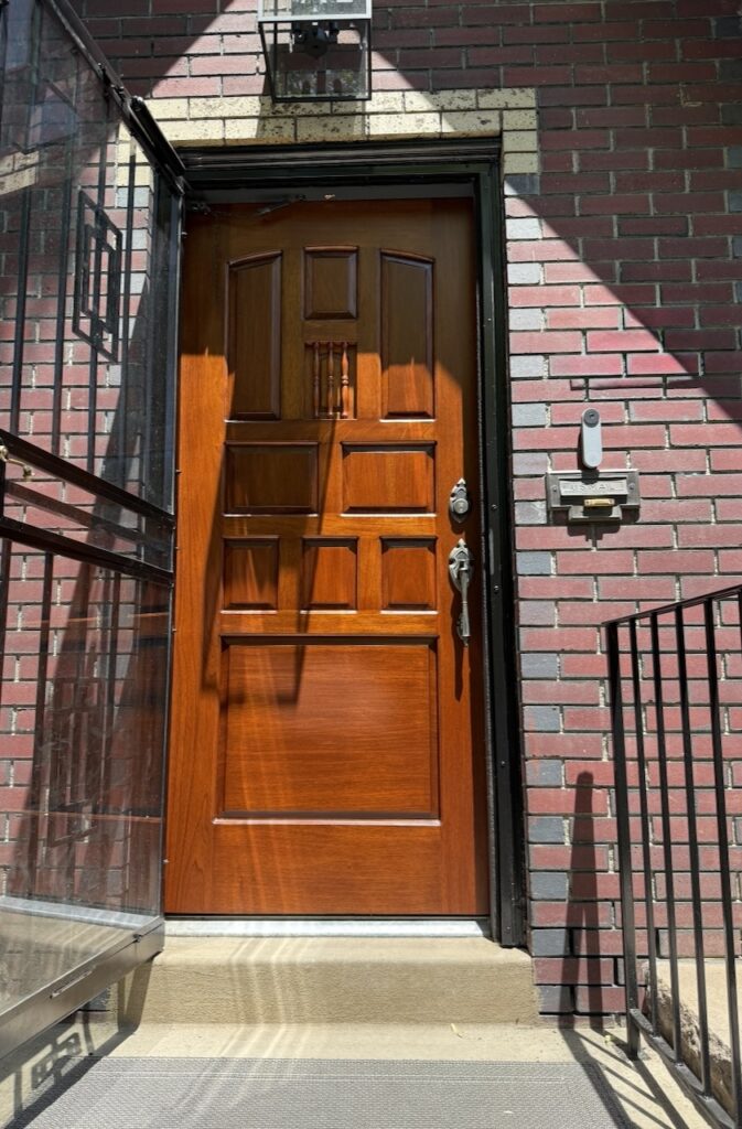 A Denver Tudor home features a wooden front door. 