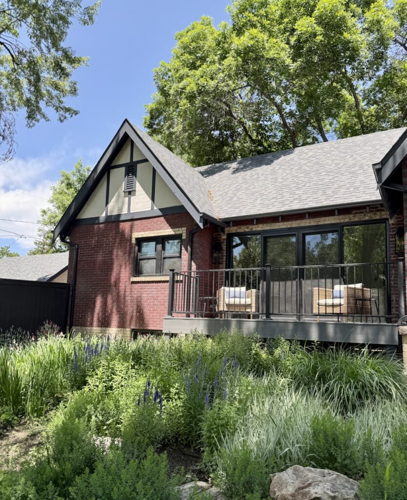 A Denver Tudor home features a front porch with cool gray decking and a cool gray roof.