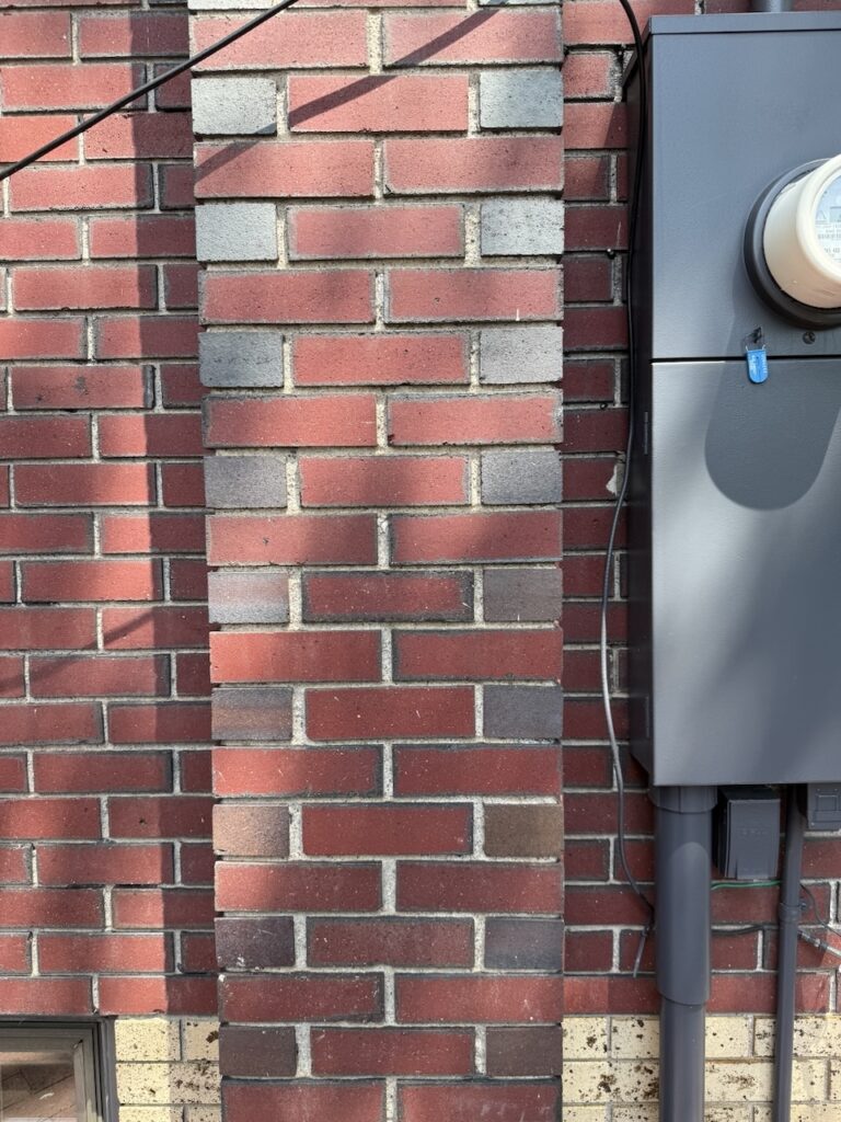 A home features red brick with blue stain as part of a modern Tudor exterior color palette.