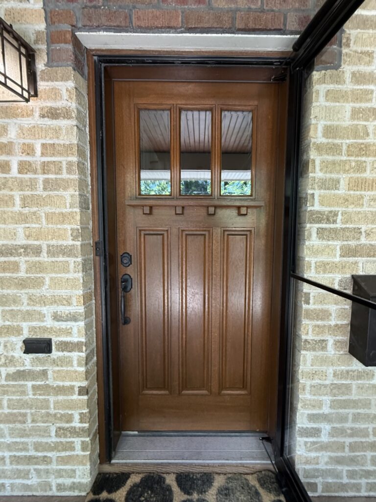 A wooden front door with buff brick surround. 