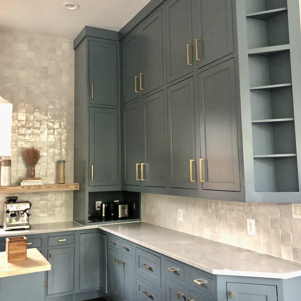 Beautiful Blue Spruce kitchen cabinets are paired with square white tile and white countertops in this kitchen.