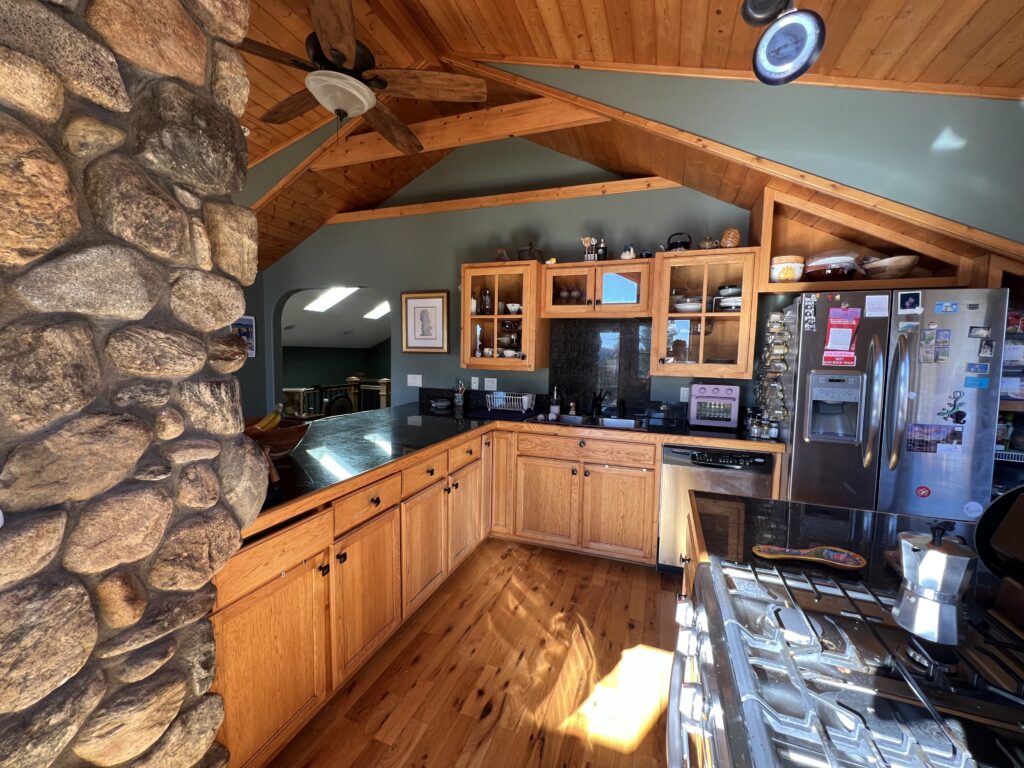 A kitchen with warm wood cabinets, ceiling and floors and Cambridge Green walls.