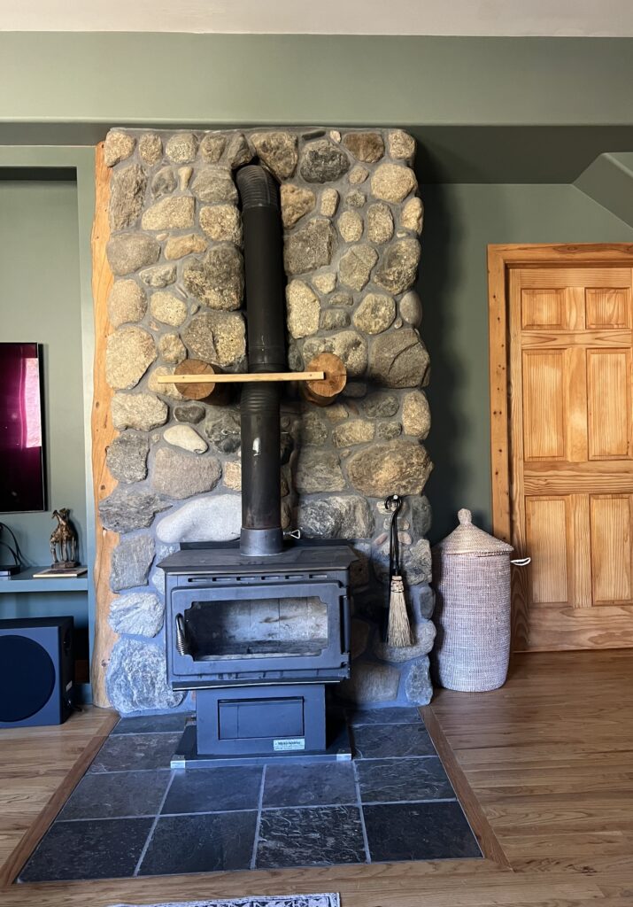 A living room with Cambridge Green walls and stone fireplace.