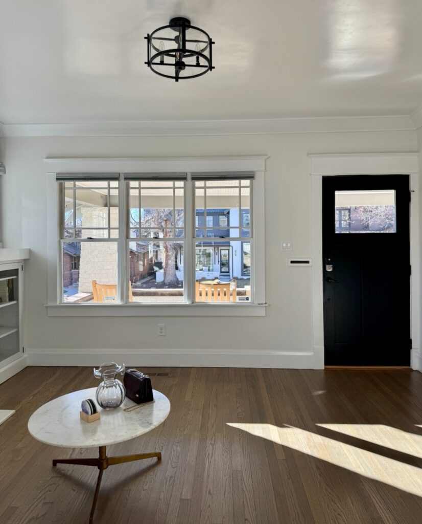 A living room and entryway painted with Benjamin Moore Dove Wing, a complex cream paint color.