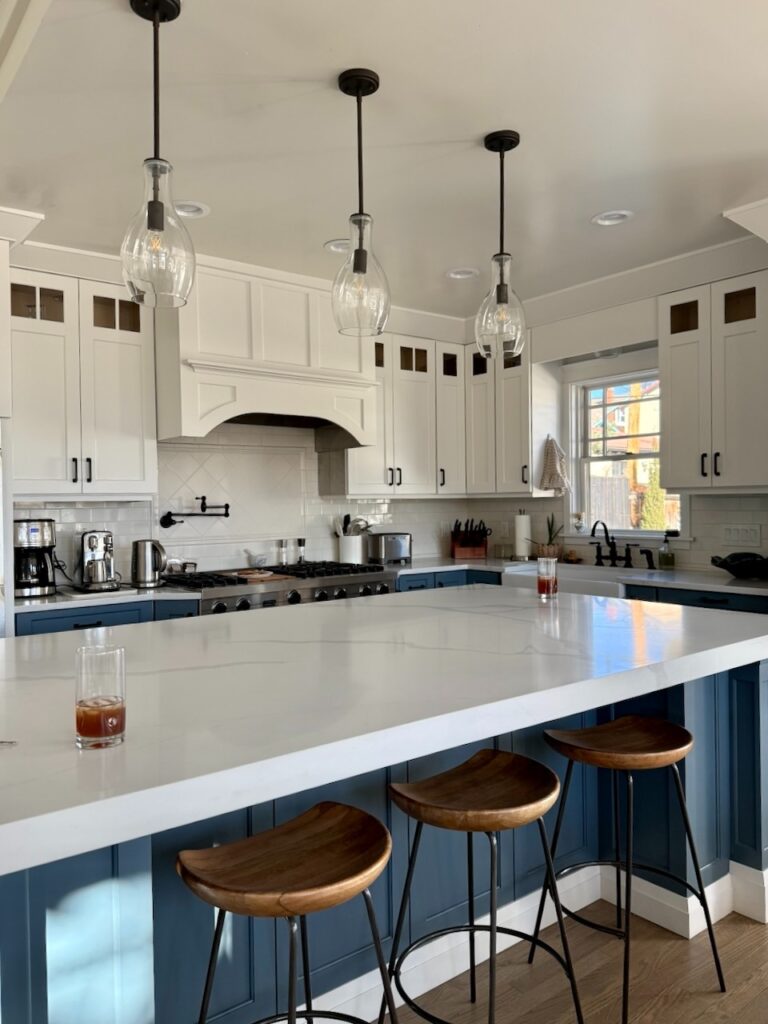 A kitchen with BM White upper cabinets, BM Phillipsburg Blue lower cabinets and BM Dove Wing walls.