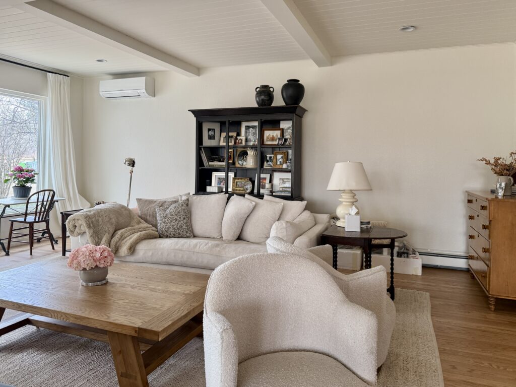 A living room is painted with Sherwin-Williams Creamy off-white paint, with a cooler white ceiling.