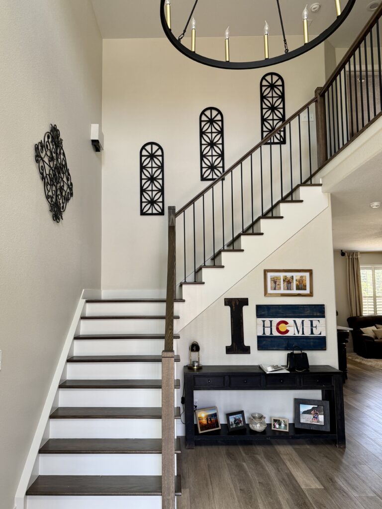 A stairwell and entryway painted with Benjamin Moore Ballet White paint with black accents and hard finishes.