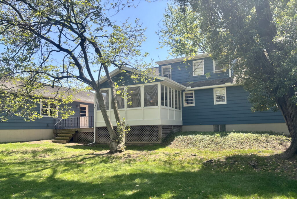 A home features a SW Waterloo exterior paint color palette, including a SW Pearly White sunroom.