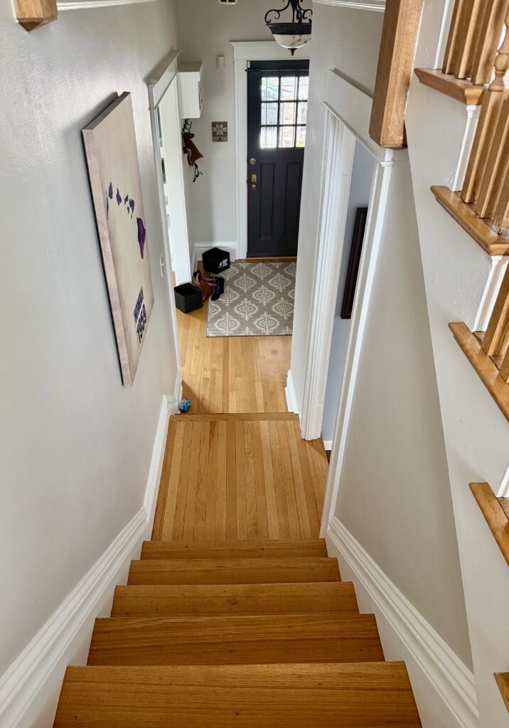 A stairway painted with BM Pale Oak walls, leading down to a BM Wrought Iron front door.
