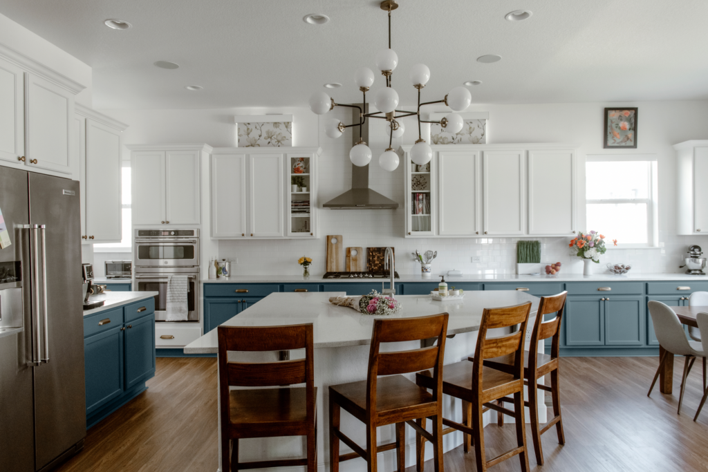 A kitchen featuring white upper cabinets and Sherwin-Williams Blustery Sky lower cabinets.