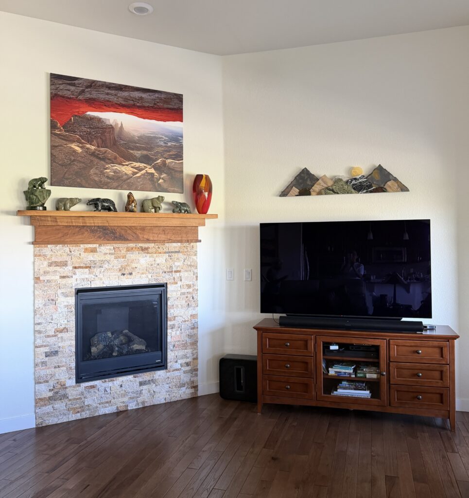 A living room painted with Sherwin-Williams Dover White features a fireplace and colorful art over the the mantle.