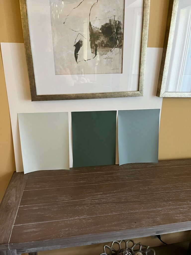 Testing Sherwin-Williams Basil alongside other paint colors in a low-lit office.