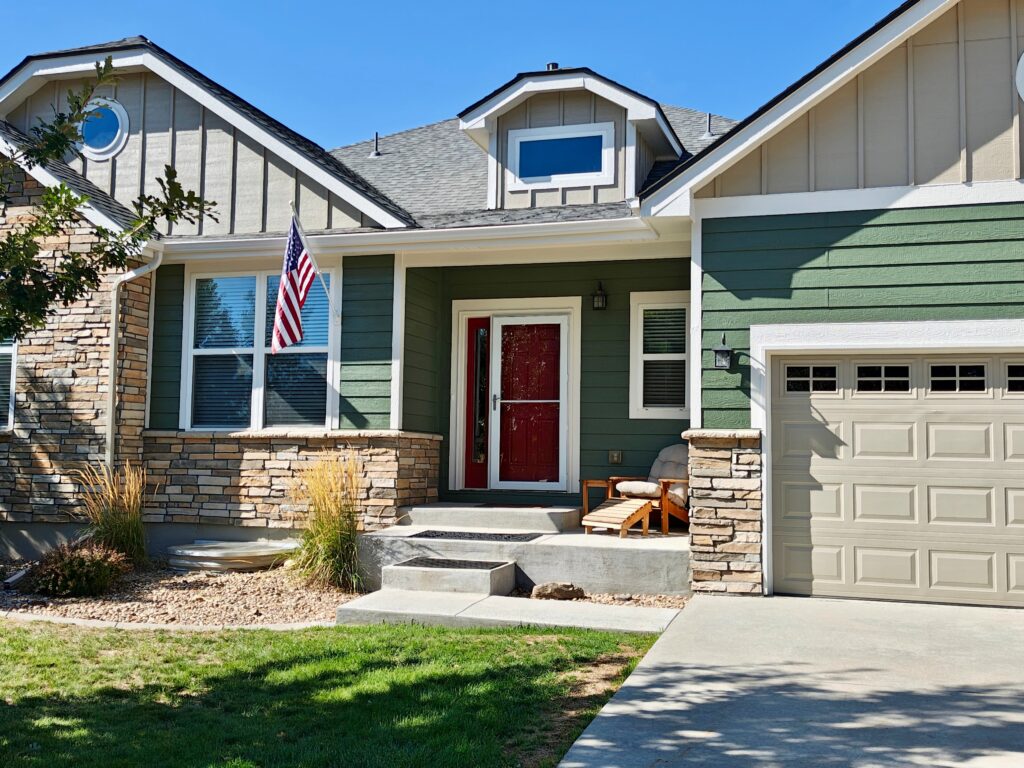 Front door and sidelight painted Sherwin-Williams Stolen Kiss (SW 7586) on a Sherwin-Williams Rosemary (SW 6187) house with warm stone, sunny lot, Colorado