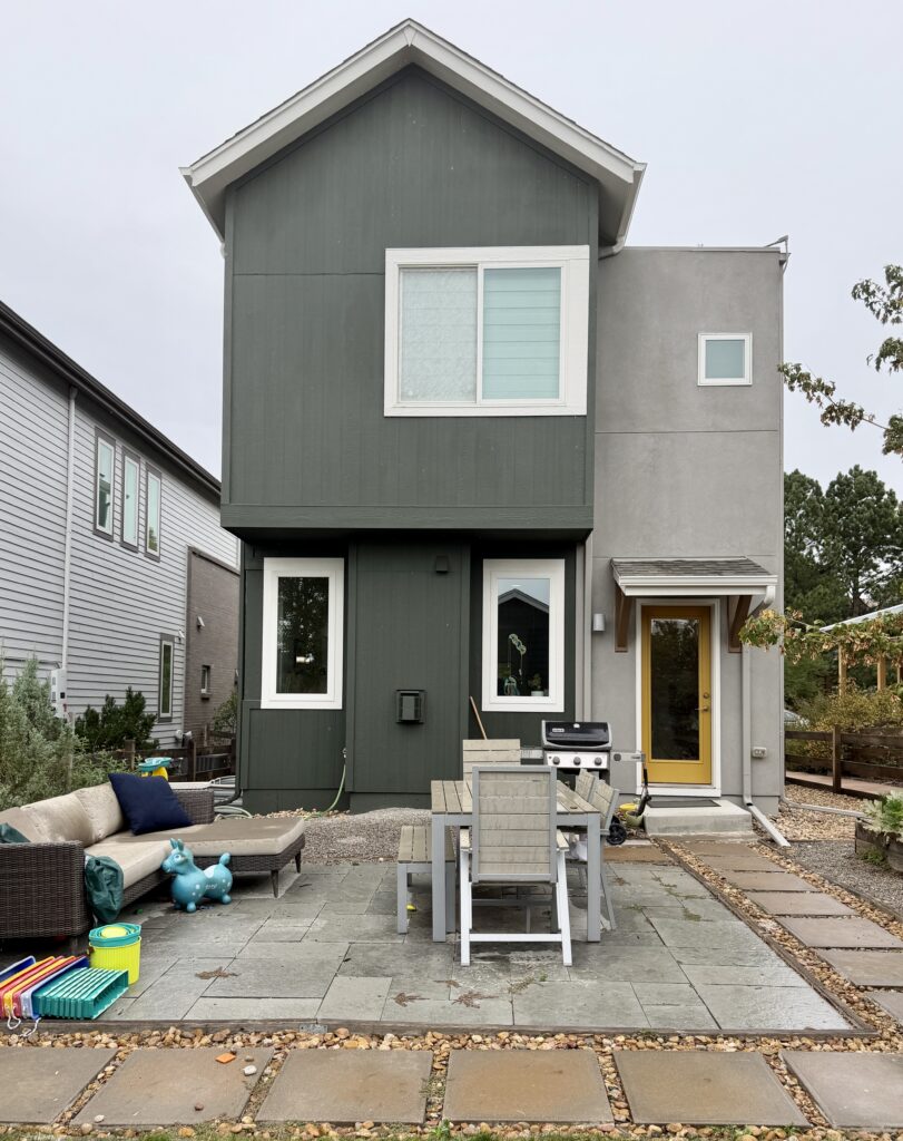Back view of suburban home painted with SW Laurel Woods siding, SW Dorian Gray stucco, Egret White trim, and SW Bosc Pear front door