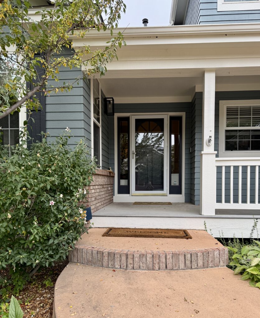 A home with BM Apollo Blue exterior paint, SW Pearly White front porch ceiling and railings and an SW Cyberspace front door.